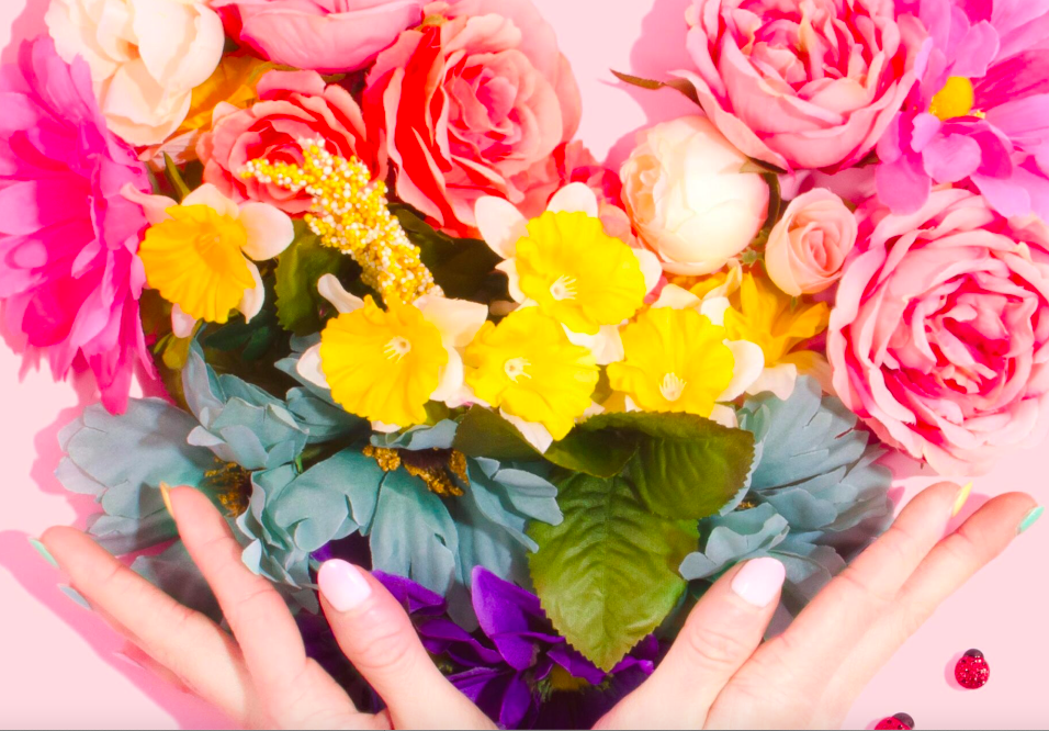 A woman 's hands are holding flowers in front of her face.