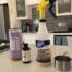 A bottle of cleaner, spray and a pot on the counter.