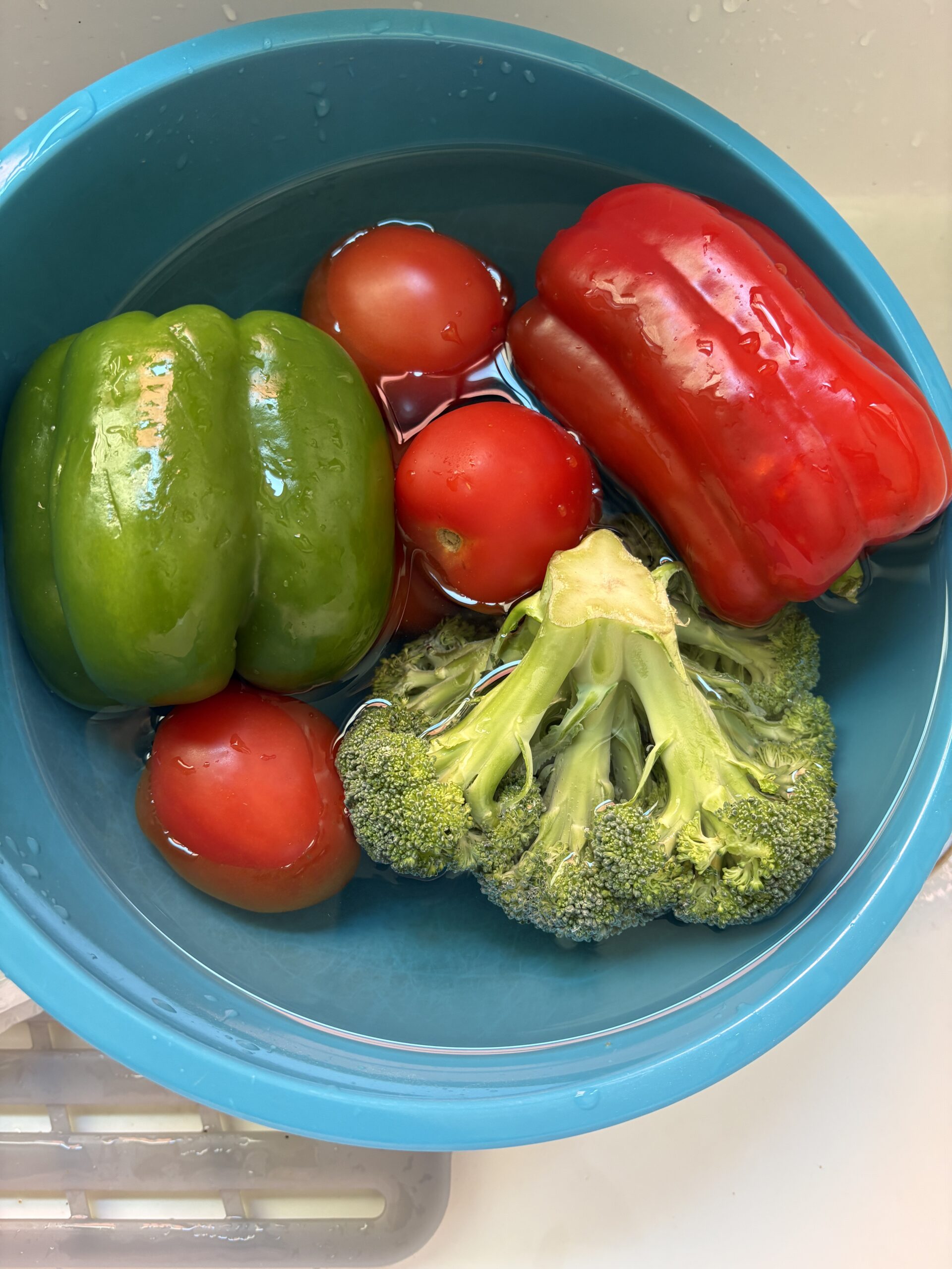A bowl of fresh vegetables soaking in water with baking soda for washing.